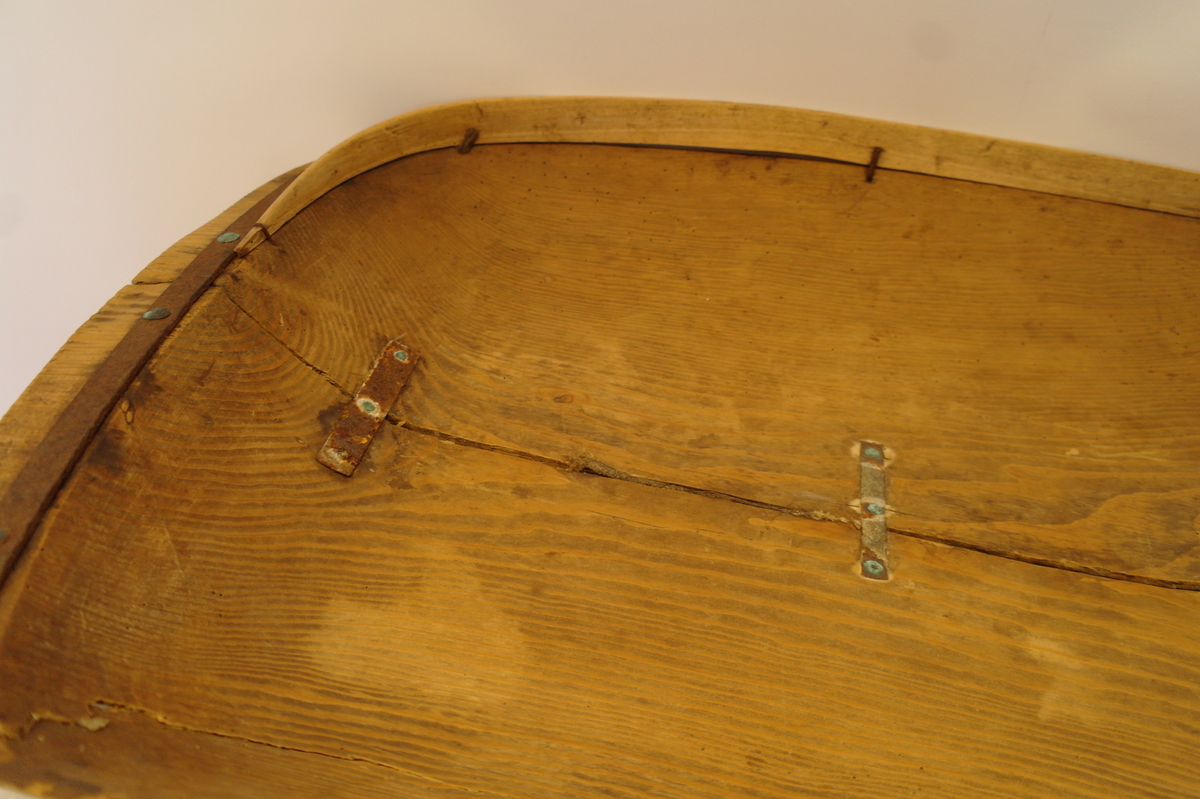 Trau i tre. Hola ut av eit stykke. Rektangulær og med runda buk. Handtaka på kortsidene er beslått med jarn. Ein stor sprekk går på langs frå handtak til handtak. Den er reparert med tre jarnbeslag. På den ene langsida er det satt på eit "skvettbord" festa med tau og spikrar.