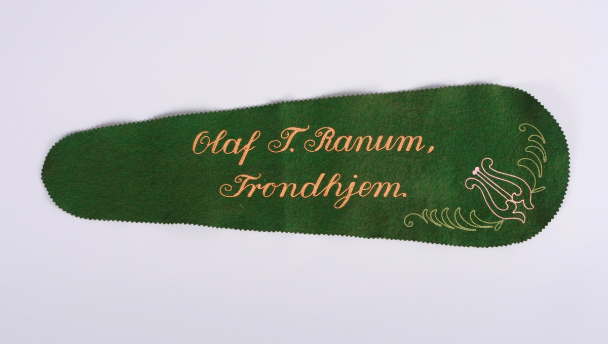 Filtduk til beskyttelse av en fiolin lagt i kasse.
Duken er dekorert med bokstaver og en lyre.