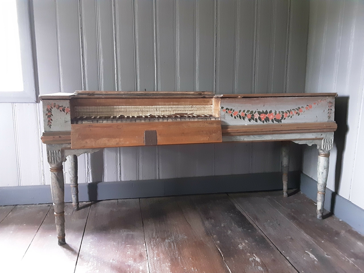 Taffelpiano , rettvinklet form. Kassa står ganske løst på 4 dreide bein. Malt utvendig på fronten med rankedekor i klassisk stil. Understellet er malt lys grått med grå-blå marmorering. Fra registrering:  "Spinett. Tre, jernhengsler, beinkledde tangenter." I protokoll anslått til å være fra 1790.