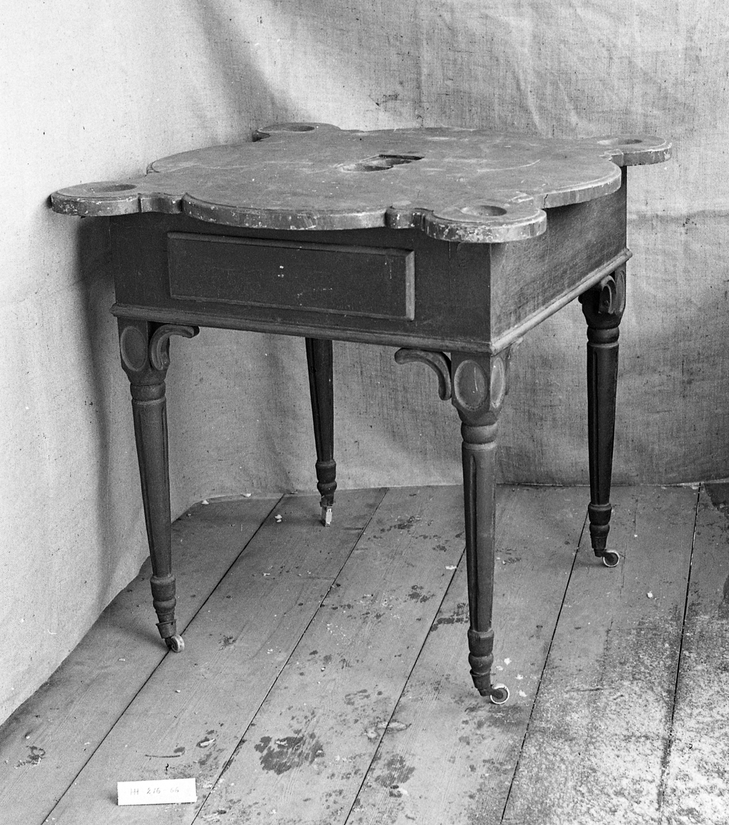 Bordet er laget av heltre og malt. Bordplaten kan ha hatt en fase med grå farge som ses der dagens malingslag er borte. Har nå en meget godt malt etterligning av marmor på bordplata. 1 skuff med profilerte kanter. Mangler knott. Dreide ben med medaljonger på øvre del. Hjørnene er forsterket med buet dekor. Den ene av disse mangler ytterste del. Alle 4 bein har hatt hjul, 2 stykker mangler. 