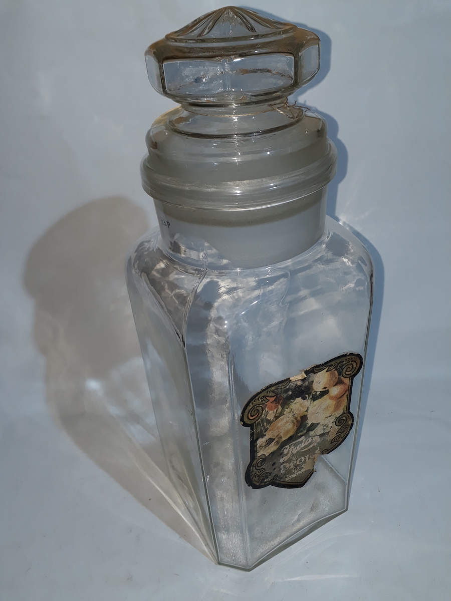 a) Standfl. sirkulær, merket "BRITISH MADE". Fire sideflater. Avrundede hjørner, rund hals.
Lokk rundt m/kuleformet håndtak. Lokk merket "2".
b) Fire store sideflater. Hjørnene er avfaset slik at det dannes fire mindre sideflater. Hals er rund. Lokk med åttesidet håndtak. Toppflate lokk m/12-bladet rosett. Etikett på sidefl. merket "Freia Drops", "fin og forfriskende". Forøvrig er det avbildet en del frukter på etiketten.
c) Formet som b, bortsett fra at rosetten på toppen av lokket er mindre, og har 16 blad. Etikett som b (noe slitt).
d) Som c.
e) Som c.
f) Fire store sideflater. Hjørnene avfaset slik at det dannes fire mindre sideflater. Den største sideflata tjener som standflate. Hals skråstilt på endeflate. Lokk, rundt merket "Freia". Håndtak på lokk er kuleformet.
g) Som f. Inneholder tørket appelsinskall.