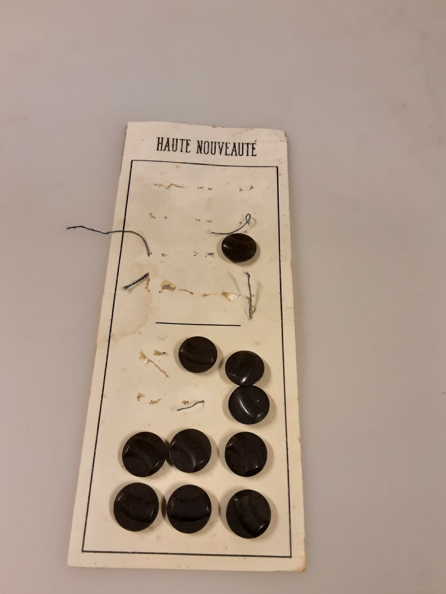 Merket «Haute nouvlauté». Plass til 24 knapper, 10 igjen. Mønstret, knappehull bak.