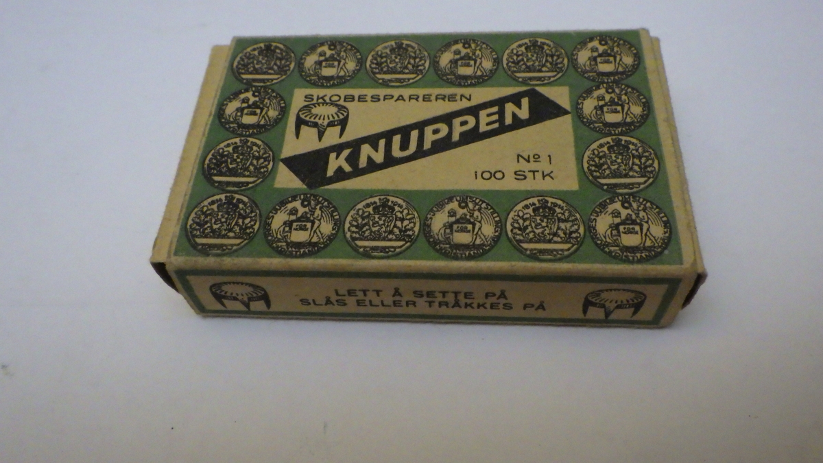 Skobespareren av stål, esken av papp. Skobespareren er sirkelrund og har tre tagger. Esken er rektangulær, til å åpne i begge
ender. Trykk i grønt og sort.