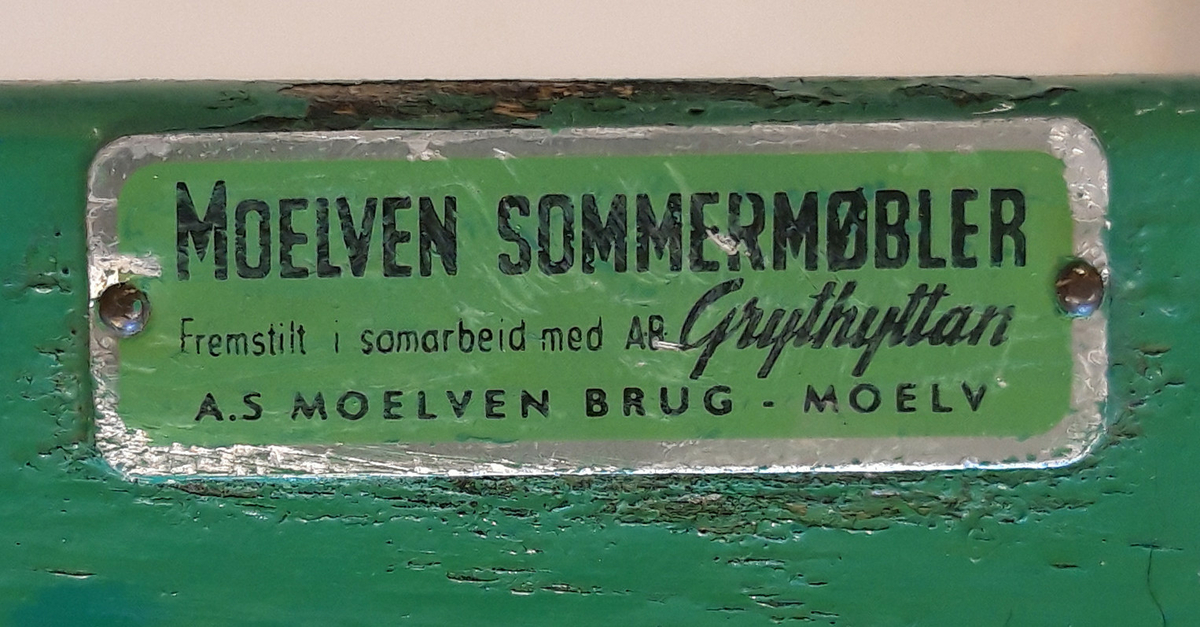 Ett rundt bord med 10 grønnmalte planker som bordplate. Understell av oransjemalt metall. Hull og feste for parasoll.  Stolene er laget av fjærstål som gir mulighet for svikt.