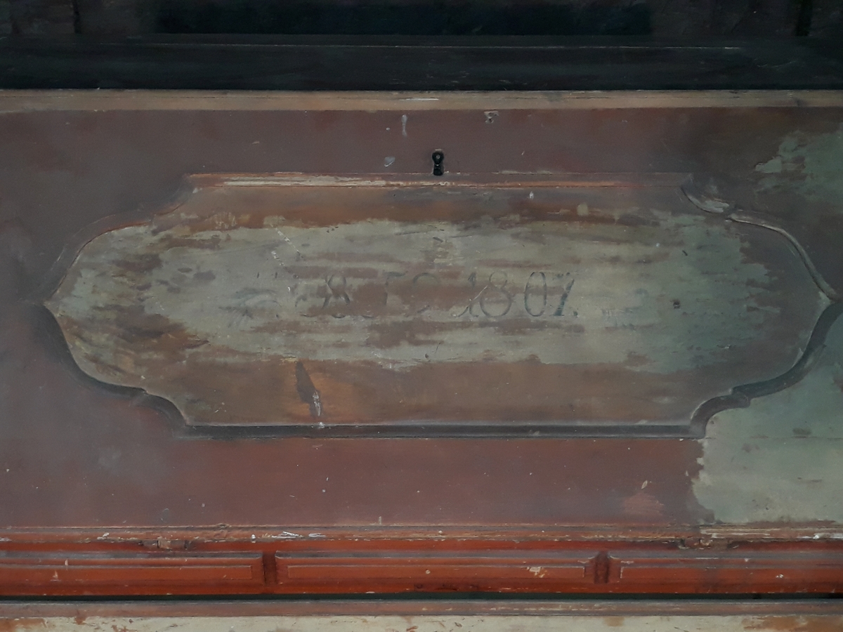 Skatoll med 3 skuffer. Skatollet er delvis avdekket. På skriveklaffens framside ses bokstavene B, J og noe uklart og årstallet 1807. Kan ha hatt overskap.