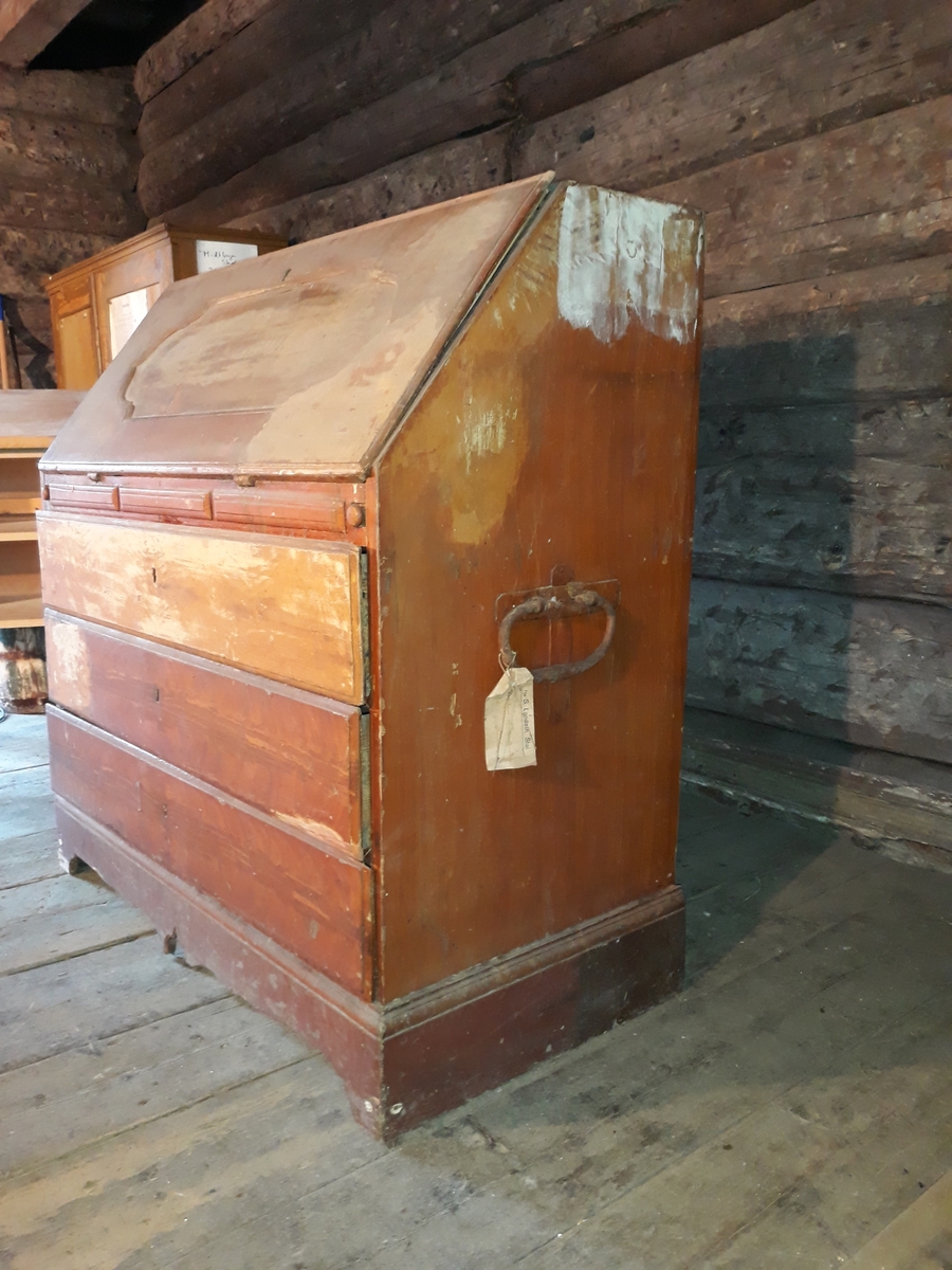 Skatoll med 3 skuffer. Skatollet er delvis avdekket. På skriveklaffens framside ses bokstavene B, J og noe uklart og årstallet 1807. Kan ha hatt overskap.