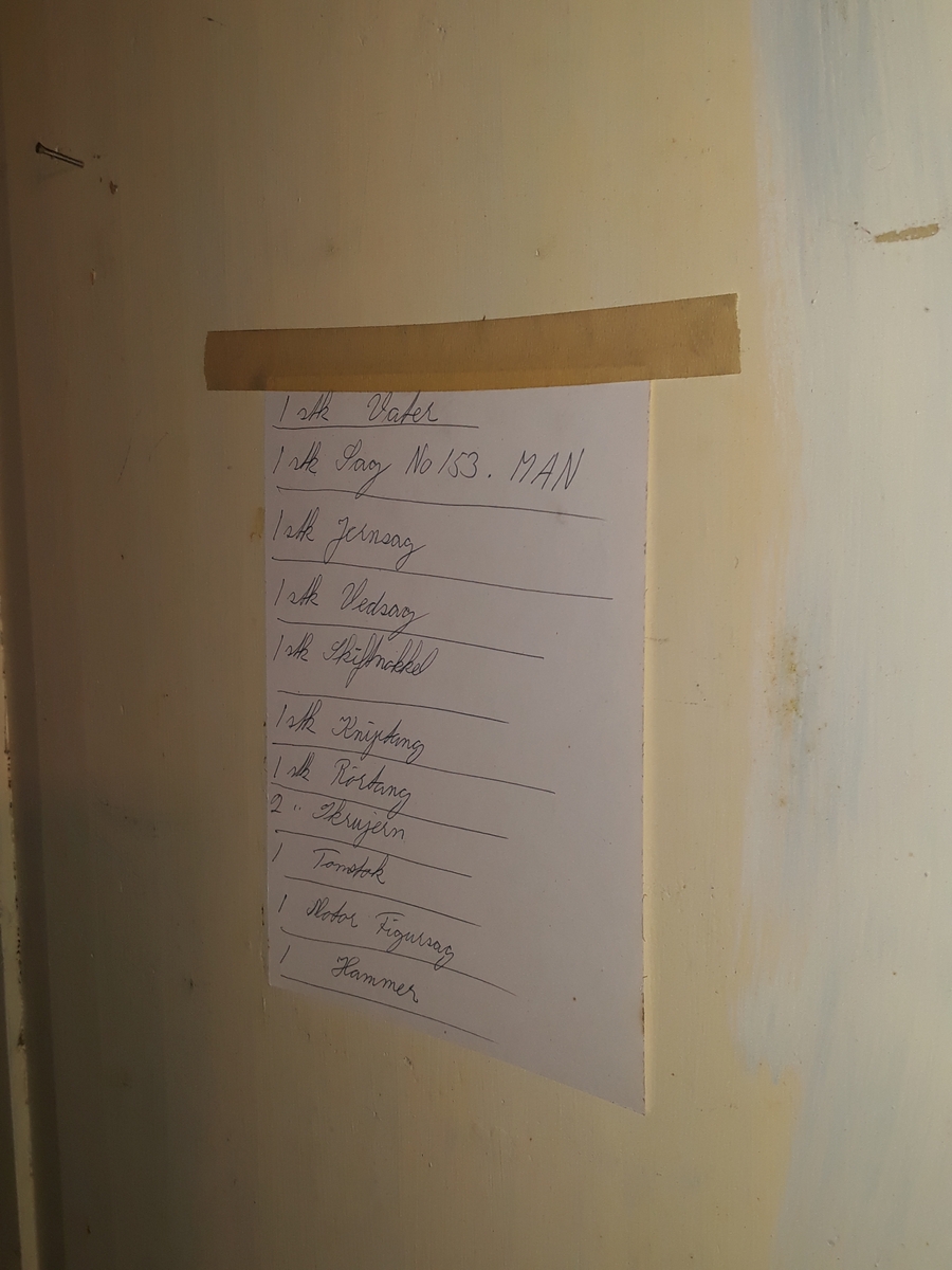 Skoleskap fra Midtbyen skole. Høyre bakbein mangler. Inventarliste over snekkerredskap på ene skapdøras bakside.