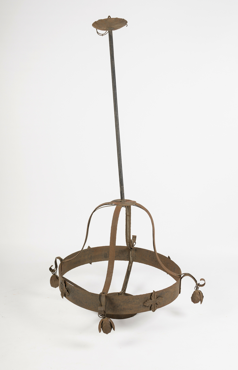 Lampe laget av jern. Har opplegg for elektrisk lys med 5 sokler for lyspærer. Det er skrufeste for kuppel i den lille jernringen.