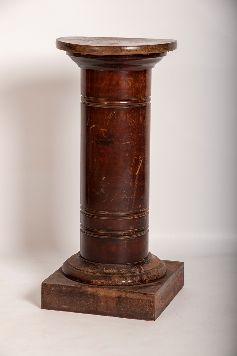 Rund pidestall av beiset og lakkert tre. 