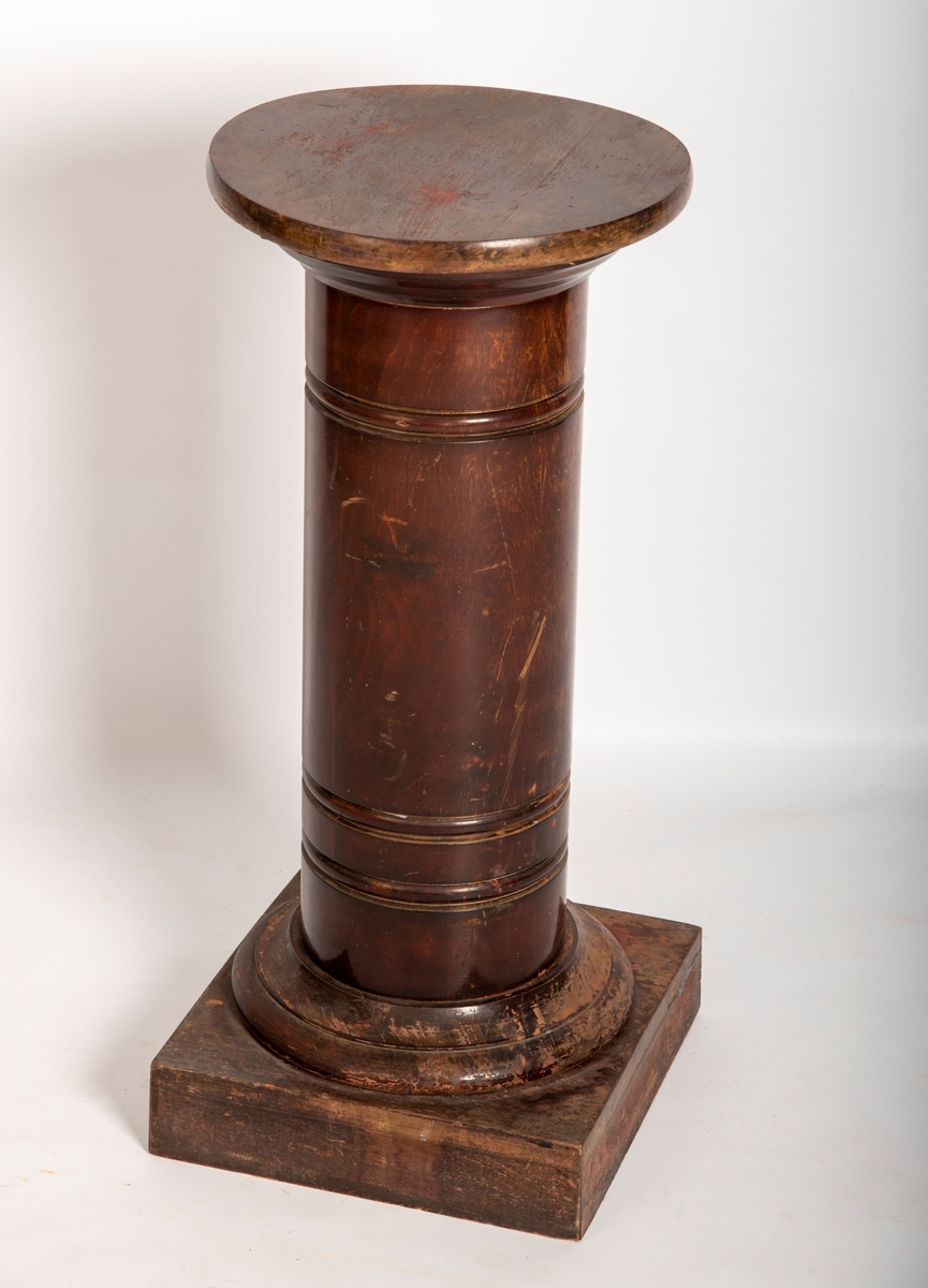 Rund pidestall av beiset og lakkert tre. 