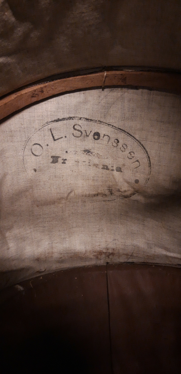Flettet kurv med avlange trekuler som holder grenene sammen. Beiset og lakkert. Innsiden er trukket med kunstlær; pegamoid. kalesje av svart kunstlær med 2 sidegardiner av ull påsydd agramaner. Understell av metall med 4 metallhjul uten noen form for dekk. Buet metallstenger med trehåndtak imellom som styre. . 