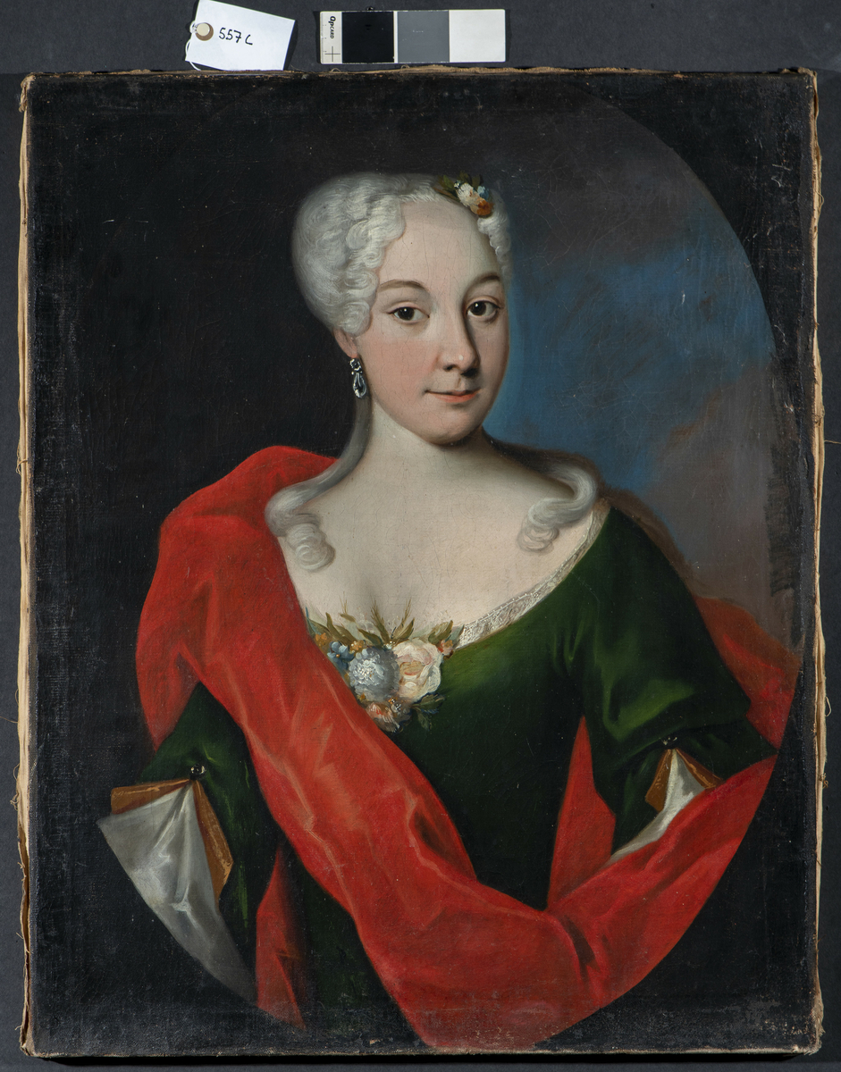 Portrett av ukjent kvinne, 1700-tallet, brystbilde, vendt svakt mot venstre. Trekvart profil og hodet er vendt høyre, med blikket mot betrakter. Mørk grønn utringet kjole med blondekant og blomsterdekorasjon. Øredobb i hennes høyre øre. Lyst oppsatt hår, lange lokker over skuldrene og hårpynt av blomster. Rødt sjal er drapert over kvinnens høyre skulder og venstre arm. Blålig felt i bakgrunnen på høyre side og det er malt en mørk oval ramme rundt motivet.