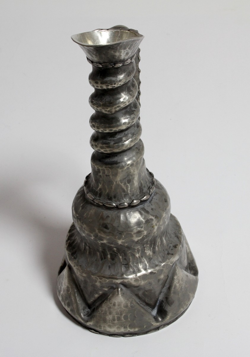 Tinnkanne frå tinnsamlinga til Hanna Rytter, som har stått på Rytterhaugen. Far til Hanna Rytter var diktaren Henrik Rytter (1877-1950). I gåvebrevet til Hol Folkebibliotek datert 1976, skriv ho: "Utanom dette er det ei lita gåve frå mi tinnsamling på "Rytterhaugen" som har hatt plassen sin i peisestova der sidan Henrik Rytter døde i 1950. Det er eit krus, ei kanne og 2 små drikkehorn som er handsmidde og kjem frå tinnsmed på Nesbyen."