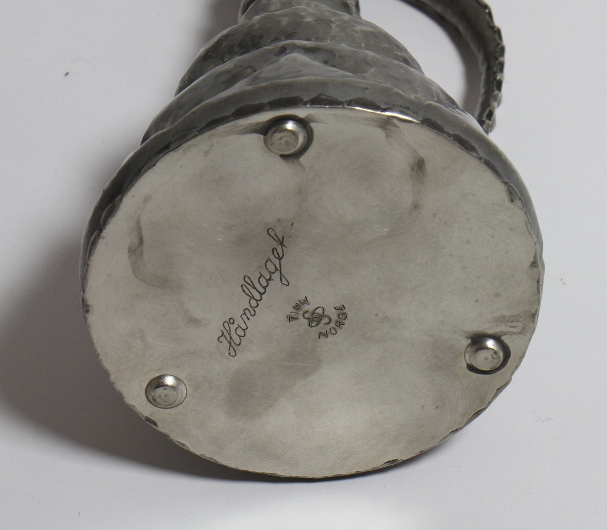 Tinnkanne frå tinnsamlinga til Hanna Rytter, som har stått på Rytterhaugen. Far til Hanna Rytter var diktaren Henrik Rytter (1877-1950). I gåvebrevet til Hol Folkebibliotek datert 1976, skriv ho: "Utanom dette er det ei lita gåve frå mi tinnsamling på "Rytterhaugen" som har hatt plassen sin i peisestova der sidan Henrik Rytter døde i 1950. Det er eit krus, ei kanne og 2 små drikkehorn som er handsmidde og kjem frå tinnsmed på Nesbyen."