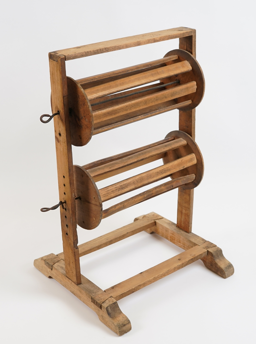 Vertikal garnvinde. Gulvståande stativ med to rullar i. Rullane har spilar og er fest til stativet med metallsteger..