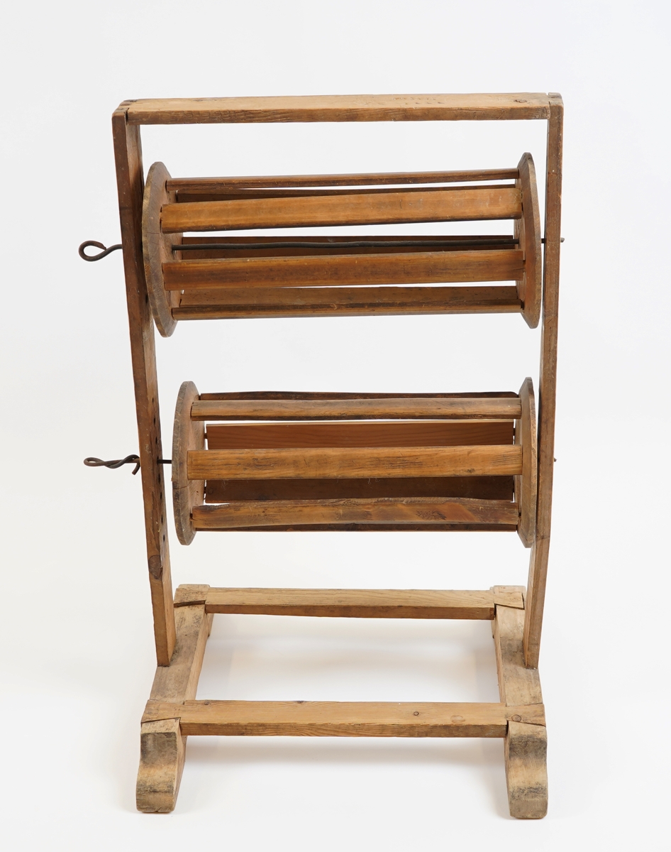 Vertikal garnvinde. Gulvståande stativ med to rullar i. Rullane har spilar og er fest til stativet med metallsteger..