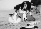 Åtta kvinnor i badkläder vid Vätterns strand. Till höger ligger deras kläder på stranden.