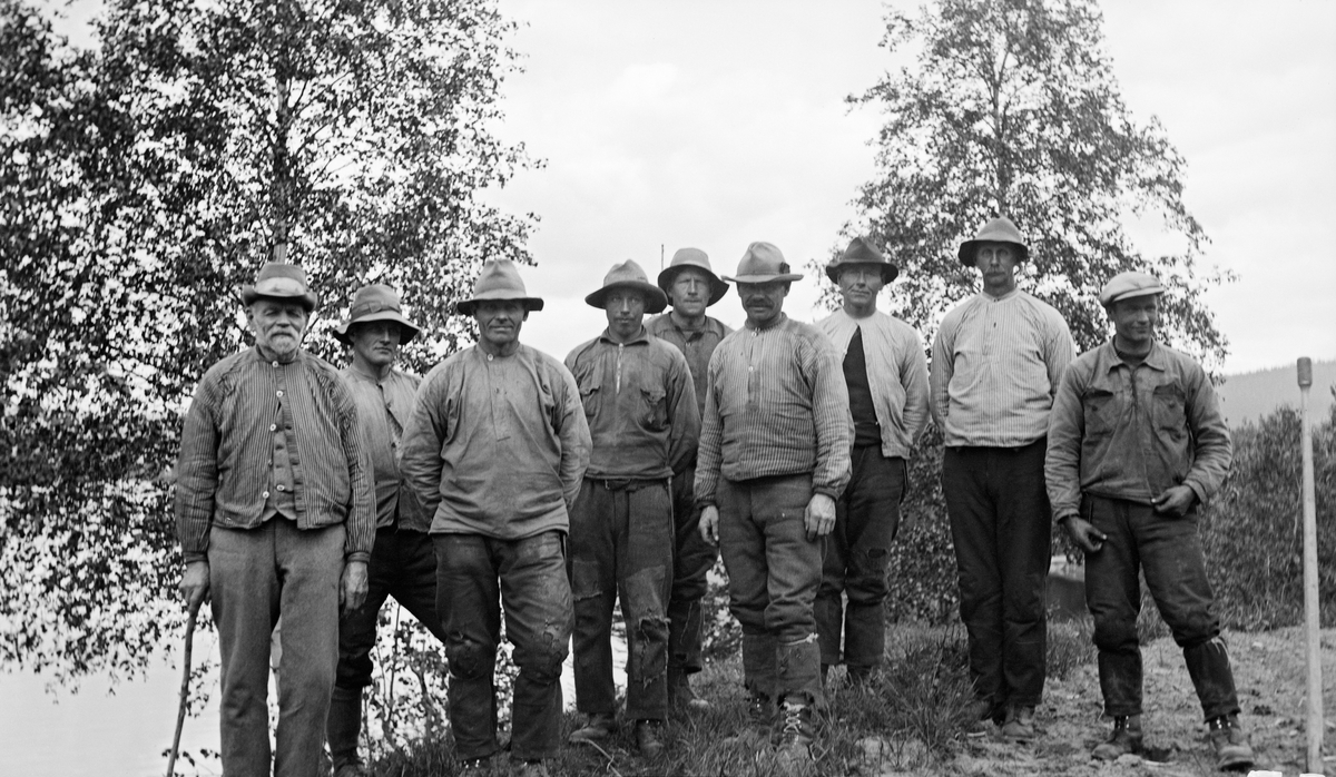 Fløterlag ved Glomma sommeren 1932.  Laget består av ni karer, som alle er iført arbeidsklær.  For de fleste av dem betyr det busseruller og hatter, grove, bøtte bukser og pluggsko.  Mannen til venstre er forholdsvis gammel og støtter seg til en stokk.  De øvrige later til å være menn i alderen 25-50 år.  Ifølge en undertekst under albumkopien av fotografiet skal dette være fløterlaget til Ole Haardnes.

Ole, i dagligtale kalt Ola Hårdnes, kom med i den såkalte langfløtinga fra konfirmasjonsalderen og fortsatte med dette arbeidet i 60 sesonger. Han ble etter hvert fløtingsformann på strekningen fra Steibrua til Rena, og skal ha fått kongens fortjenstmedalje for sitt lange arbeidsliv.