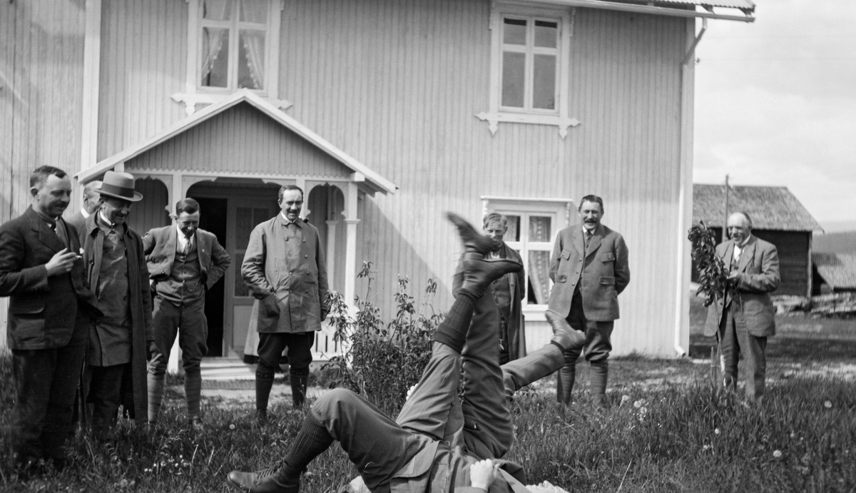 Festlig samvær under Christiania Tømmerdireksjons befaring sommeren 1919.  Fotografiet er tatt på gardstunet på Myrberget i Øvre Rendalen.  To menn ligger på bakken og spenner revkrok, åtte andre betrakter denne leken. I bakgrunnen ses det panelte våningshuset på garden med vindfanget foran hovedinngangen.  Lengre bak til høyre ses enden av en låvebygning.  Styret for Christiania Tømmerdireksjon besto i 1919 av Westye P. Egeberg, Math. Smith, Cæsar Bang, Alb. Asbjørnsen, Otto Nilsen, Olav Nergaard, Amund Bredesen-Opset, Børre Vik og Alfred [Andersen] Alten.  Johs. Johannesen var administrativ leder.

Da dette fotografiet ble tatt var Myrberget skysstasjon i Øvre Rendalen. Johannes Gudbrandsen Myrberg og hans andre kone, Maren Eriksdatter, var vertskap.

Bygningen var oppført av laftetømmer, i to etasjer, men med bordkledning både inn- og utvendig. Den opprinnelige rektangulære laftekassa hadde ei grunnflate på 107 kvadratmeter. I tillegg kom et tilbygg på 65 kvadratmeter. Som bildet viser var det også en veranda framfor inngangsdøra. Bygningen huset brukerfamilien i tillegg til overnattingsgjestene som stanset på skysstasjonen. I førsteetasje var det åtte rom, deriblant et digert kjøkken og to entréer, i andre etasje seks rom og to entréer. Dette var det eneste våningshuset på Myrberget.