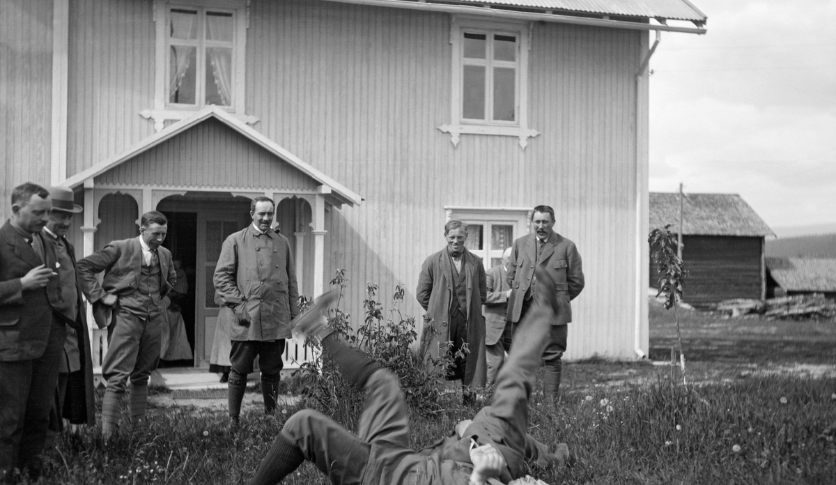 Festlig samvær under Christiania Tømmerdireksjons befaring sommeren 1919.  Fotografiet er tatt på gardstunet på Myrberget i Øvre Rendalen.  To menn ligger på grasbakken og spenner revkrok, sju andre betrakter denne leken.  I bakgrunnen ses den sørvendte panelfasaden på våningshuset på garden.  Lengre bak ses enden av en låvebygning.  Styret for Christiania Tømmerdireksjon besto i 1919 av Westye P. Egeberg, Math. Smith, Cæsar Bang, Alb. Asbjørnsen, Otto Nilsen, Olav Nergaard, Amund Bredesen-Opset, Børre Vik og Alfred [Andersen] Alten.  Johs. Johannesen var administrativ leder. Vi vet foreløpig ikke hvem av dem som er med på dette bildet.

Da dette fotografiet ble tatt var Myrberget skysstasjon i Øvre Rendalen. Johannes Gudbrandsen Myrberg og hans andre kone, Maren Eriksdatter, var vertskap.

Bygningen var oppført av laftetømmer, i to etasjer, men med bordkledning både inn- og utvendig. Den opprinnelige rektangulære laftekassa hadde ei grunnflate på 107 kvadratmeter. I tillegg kom et tilbygg på 65 kvadratmeter. Som bildet viser var det også en veranda framfor inngangsdøra. Bygningen huset brukerfamilien i tillegg til overnattingsgjestene som stanset på skysstasjonen. I førsteetasje var det åtte rom, deriblant et digert kjøkken og to entréer, i andre etasje seks rom og to entréer. Dette var det eneste våningshuset på Myrberget.