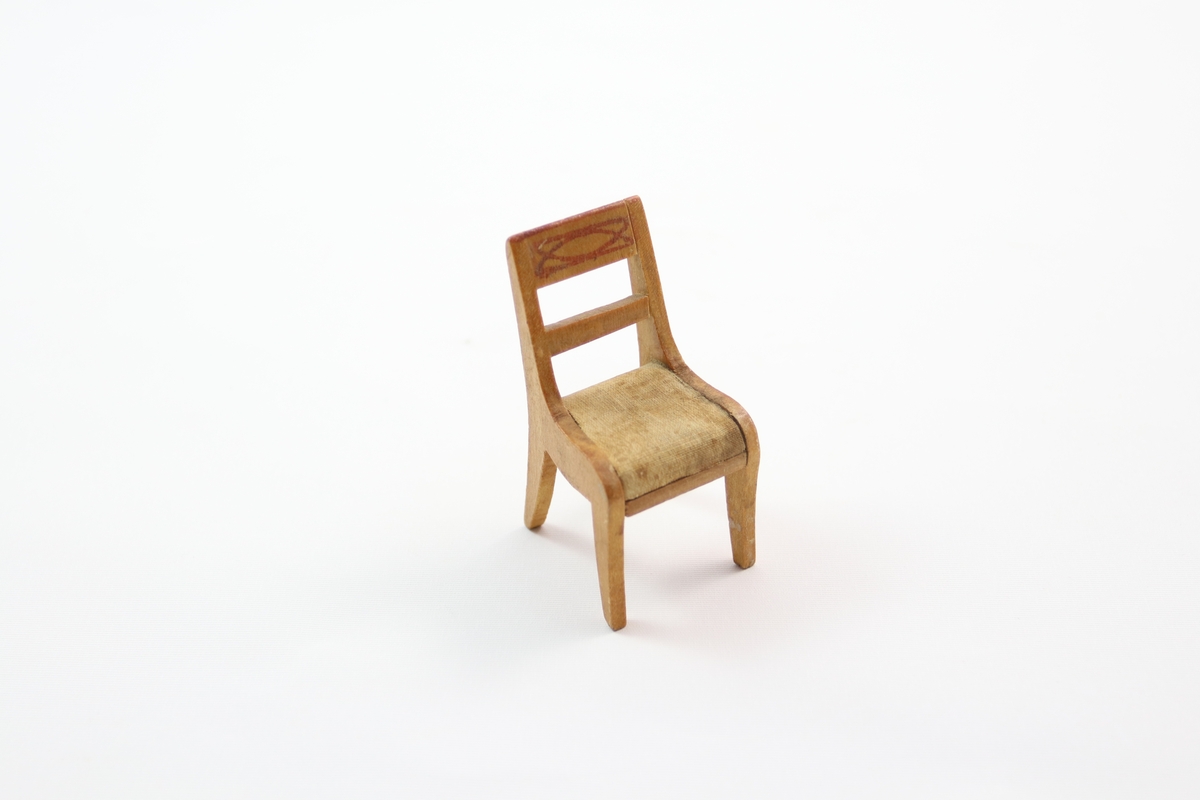 Dukkemøblement i nyklassisistisk stil med ni hoveddeler laget av lyst trefinér.

a. og b. bord med rektangulær plate, fire pålimte ben og sidelister. Malte rød-brune kanter og dekorativ rute-form i midten av bord-flaten.

c, d, e og f. er spisestoler. Sidelistene til rygg, sete og bein er laget av ett stykke, med tversgående pålimte lister. Sete av hvitt lerretstoff. 

g. Klassisk eller romersk sofa. Rektangulær bunn og sete trukket med lerret. To buede sittestykker på kortsidene og to pålimte buede bein. Malt dekor på langside.

h. Kommode. Rektangulær med to skuffer. Kortsidene er forlenget til fire rette ben.

i. Seng med sengeutstyr. Rektangulær, med buede sidestykker og rette gavler som er forlenget til fire ben. I senga ligger en madrass av lys blå silke 741i3, pute av samme stoff 741i4, dyne med påsydd blondekant 741i1 og hvit bomullspute med blondekant 741i2.