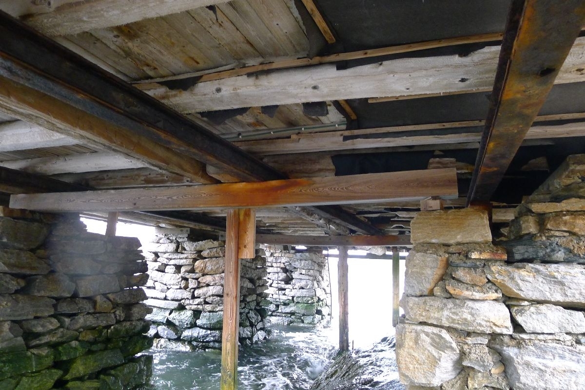 Rødmalt brygge på stabber av murt stein. Bordkledd og bordtak. 137 m2 grunnflate, totalt areal 240 m2. 