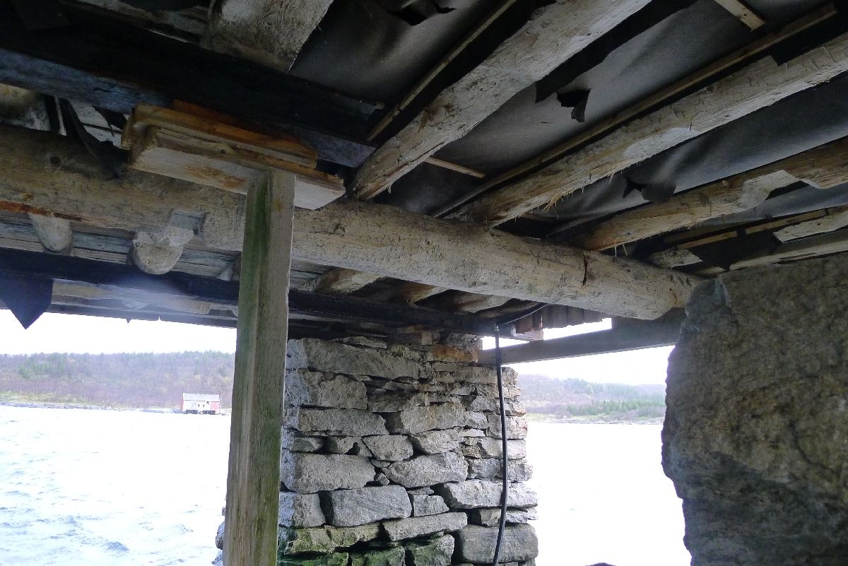 Rødmalt brygge på stabber av murt stein. Bordkledd og bordtak. 137 m2 grunnflate, totalt areal 240 m2. 