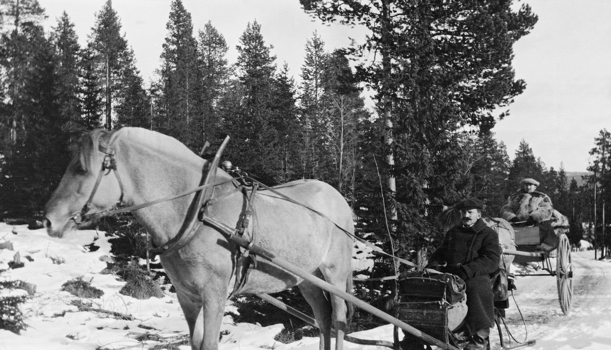 Vintertransport i Atndalen, antakelig fotografert seint på vinteren 1917.  Fotografiet viser to reisende på en snø- eller isdekt veg gjennom et landskap med glissen furuskog.  I forgrunnen en fjording forspent en «husk» (sledetype) der det sitter en mann med svart frakk og hatt.  Bakenfor nok en fjording med kjerre.  I kjerra sitter en pelskledd kar med skyggelue.  Det er nærliggende å tru at de to herrene representerte Glomma Fellesfløtingsforening, og at de var på veg for å besiktige byggearbeidene ved Atnsjødammen.