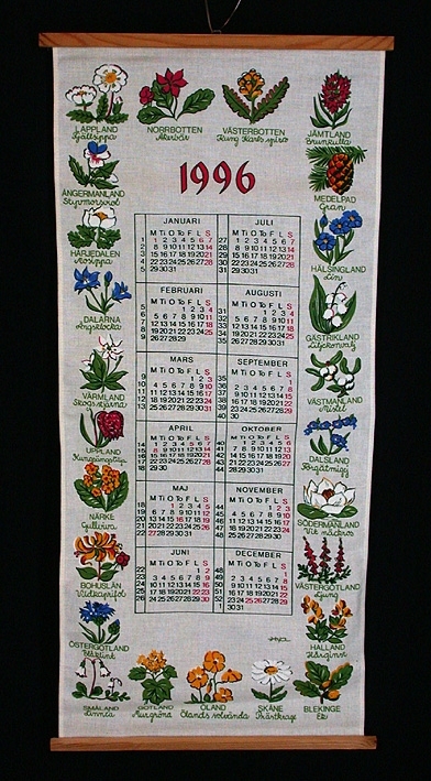 5 st väggalmanackor med färgtryck på linnetyg. 

:1 Almanacka från 1970. Brunbetsad trälist i över- och underkant. Själva almanackan i vitt, svart och rött. Ram och överstycke mörkt blågrönt med en slinga av blå blommor samt ett motiv med en ryttare till häst i folkloristisk stil. Längd 900 mm, bredd 305 mm.

:2 Almanacka från 1974. Brunbetsad trälist i över- och underkant. Oblekt linnetyg med tryck i orange, svart, grönt, gult och vitt . Själva almanackan omges på båda sidor av stjärntecken. Överstyckets motiv består av solen, månen, planeter och stjärnbilder. Längd 525 mm, bredd 330 mm. 

:3 Almanacka från 1985. Antikbetsad trälist i över- och underkant. Oblekt linne med tryck i brunt, rött, grönt, gult, blått och vitt. Själva almanackan utgör drygt halva längden, däröver 4 st motiv - ett för varje årstid. 
Längd 600 mm, bredd 320 mm.

:4 Almanacka från 1996. Obehandlad trälist i över- och underkant. Vitt, fintrådigt linne med tryck i grönt, rött, gult, blått och svart. Själva almanackan omges av bilder och namn på Sveriges landskapsblommor. 
Längd 710 mm, bredd 330 mm.

:5 Almanacka från 2000. Rund obehandlad pinne trädd i sydd kanal i tygets överkant. Vitt fintrådigt linne med tryck i blått, svart, rött, gult, grönt, brunt, rosa och grått. Själva almanackan utgör den nedre halvan av tyget. På den övre halvan avbildas en prislista med priser från år 1900 och år 2000. På båda sidor härom avbildas olika matprodukter och husgeråd. 
Längd 580 mm, bredd 350 mm.