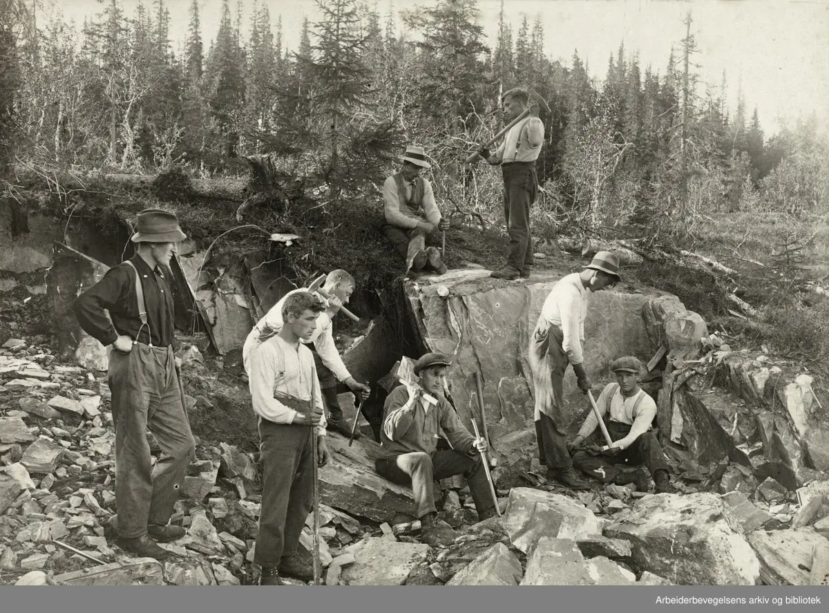 Riksveien bygges mellom Mellingsmoen og Smalåsen, Nord-Trøndelag i 1922. Foran (f.v.) Ole Stubbforsmo, Lars Stormli, Sverre Nilsen, Leif Stubbforsmo, Helge Fagerli, Undvig Kroken. Bakenfor: Ole Bergli og Petter Stubbforsmo.