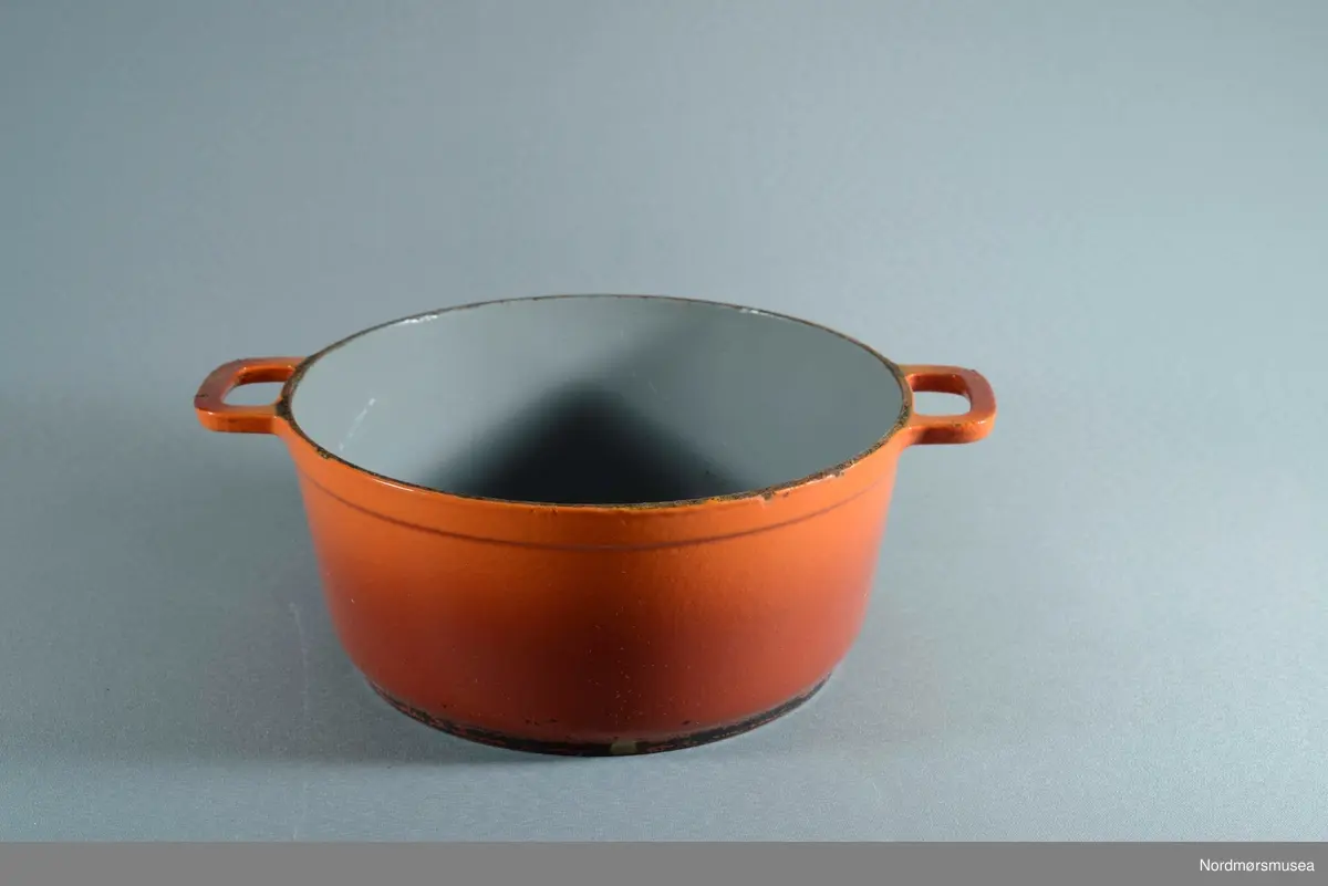 Rund jerngryte belagt med emalje. Oransje farge ytterst og grå innvendig. en hanke på hver side.