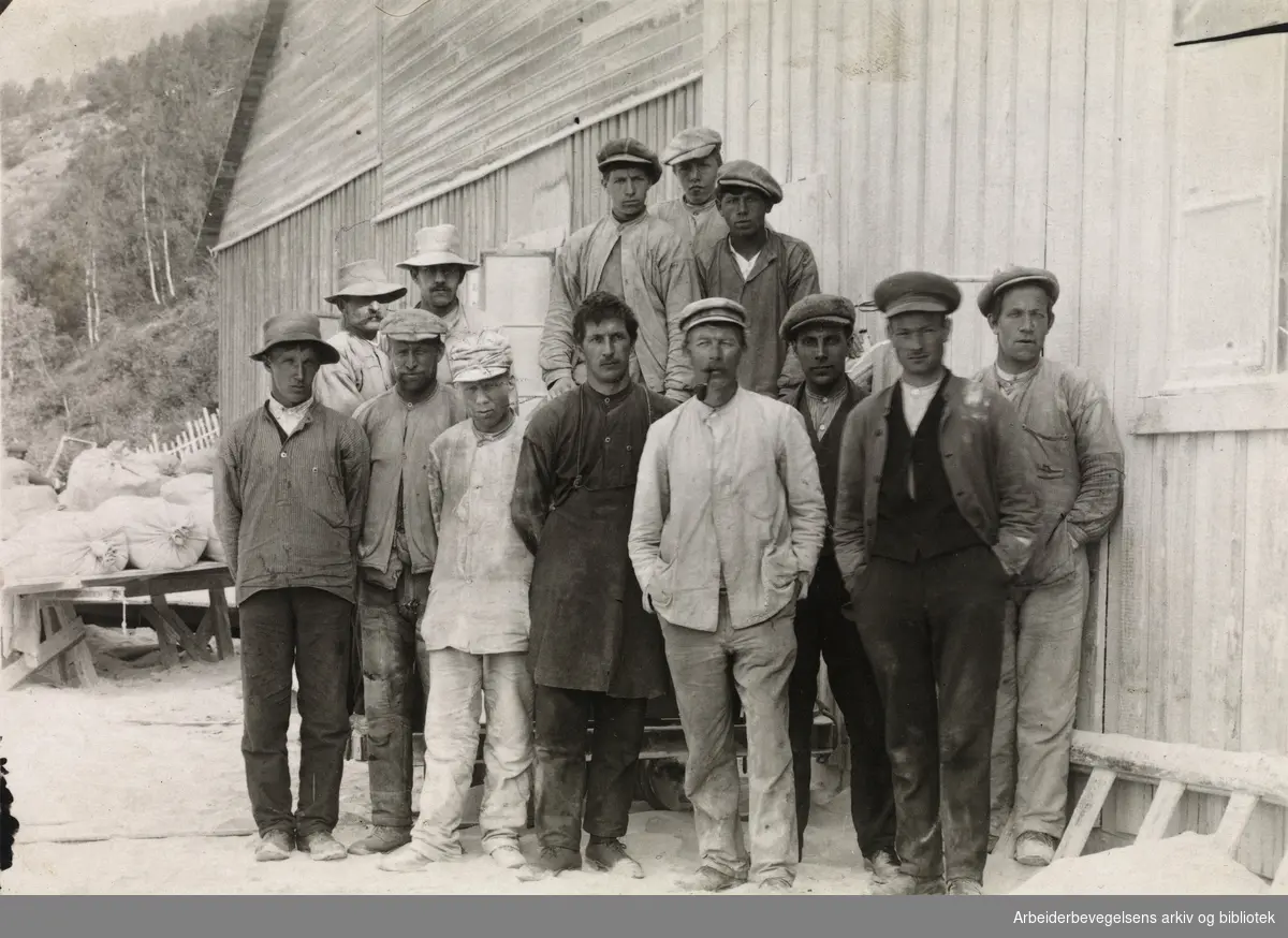 Klæbersteinsskjæreriet på A/S Norway Talcumfabrik på Bårstad, Lalm i 1914. Fra venstre: Ukjent, Lomværingen, Torstein Imersløken, Pål Berg, Sigvart Henriksen, Sogning, Jacob, Kongsvik, Ukjent, Ukjent, Einer Plassen, Jacob Bakka og ukjent.