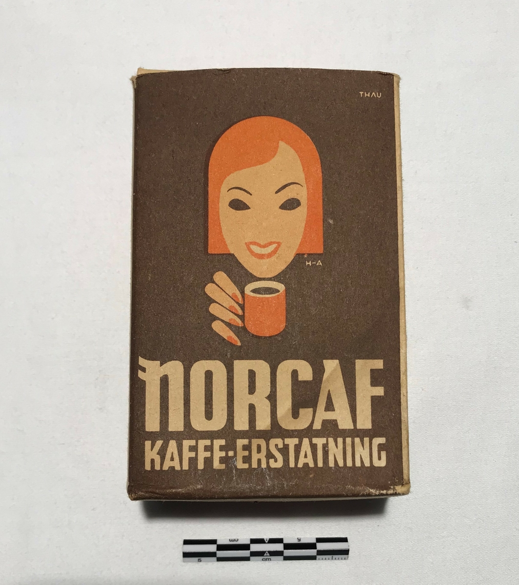 Eske av papp med kaffeerstatning. Tekst: NORCAF KAFFE ERSTATNING. På sidene står bruksanvisning på tilbereding for koking og trakting. Kaffeerstatningen ligger i esken i en papirpose.
Tidligere 2stk. Et i brygge og et i Våninghuset. Gjenstanden i brygga ble oppspist av mus og destruert under opprydning Juni 2024