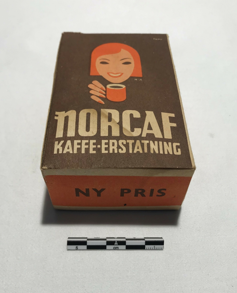 Eske av papp med kaffeerstatning. Tekst: NORCAF KAFFE ERSTATNING. På sidene står bruksanvisning på tilbereding for koking og trakting. Kaffeerstatningen ligger i esken i en papirpose.
Tidligere 2stk. Et i brygge og et i Våninghuset. Gjenstanden i brygga ble oppspist av mus og destruert under opprydning Juni 2024