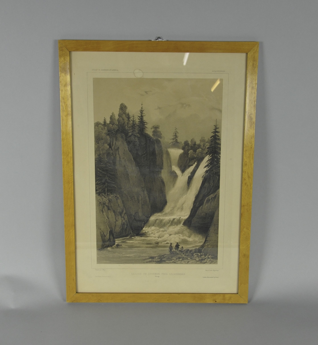 Innrammet trykk. Motiv av tre fiskere ved foss i Mesnaelva, Lillehammer. Trykket har en ramme av lysebrunt tre, som er oljet.