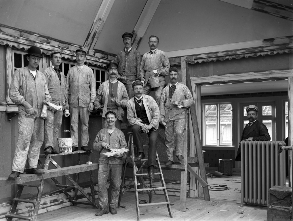 Fotografen Gustaf Nilsson utökade sin verksamhet och behövde då en ny ateljé. Den kom att ligga vid Krokshall i hans nybyggda hus Strömsberg, som stod klart 1909. På bilden syns en stor skara hantverkare i färd med att inreda den nya ateljén. Ett varmvattenelement syns också - en verklig nymodighet.