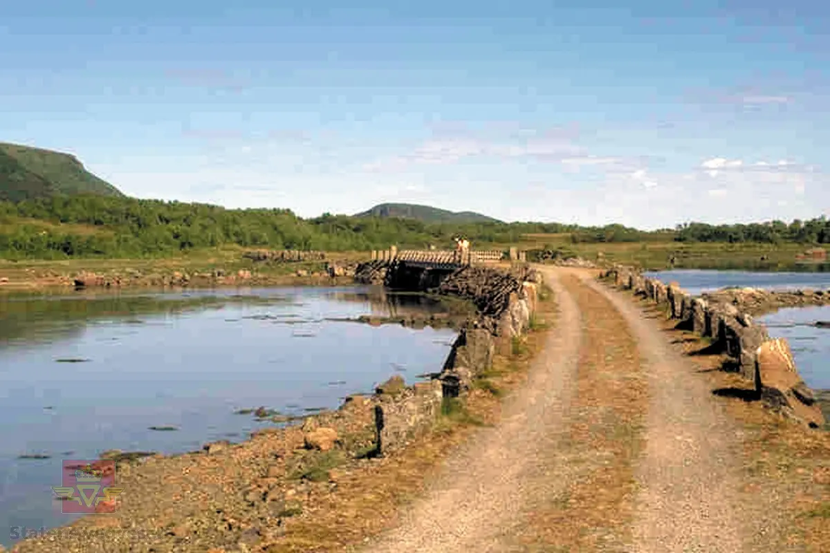 Bilde 1)  Kjøreveg fra 1922-1934. Fv.935. Strengelvåg fyllinga. 
Bilde 2) Refererer til bilde og informasjon Nr. 119 "Anlegget" Øksnes, Nordland, jf. Nasjonal verneplan, for veger, bruer og vegrelaterte kulturminner. Statens vegvesen - Region nord.  2002. 
Vegen ligger på en murt fylling i en lengde av 700 meter. På begge sider står stabbesteiner, og på midten av strekningen ligger ei nybygd stålbjelkebru på 24 meter over to spenn. Den er gjenoppbygd etter gamle tegninger og lagt på de opprinnelige brubjelkene. Brua har i dag innsnevring for å hindre motorisert ferdsel, men er i aktiv bruk som turveg.