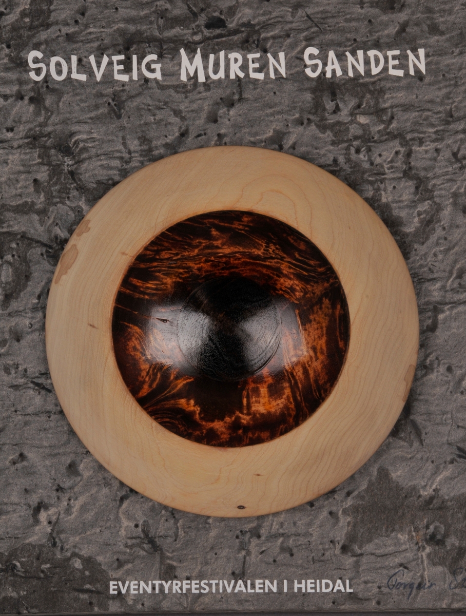 Steinplate med eit stort auge, og teksten "Trollprisen 2004 Solveig Muren Sanden Eventyrfestivalen i Heidal".