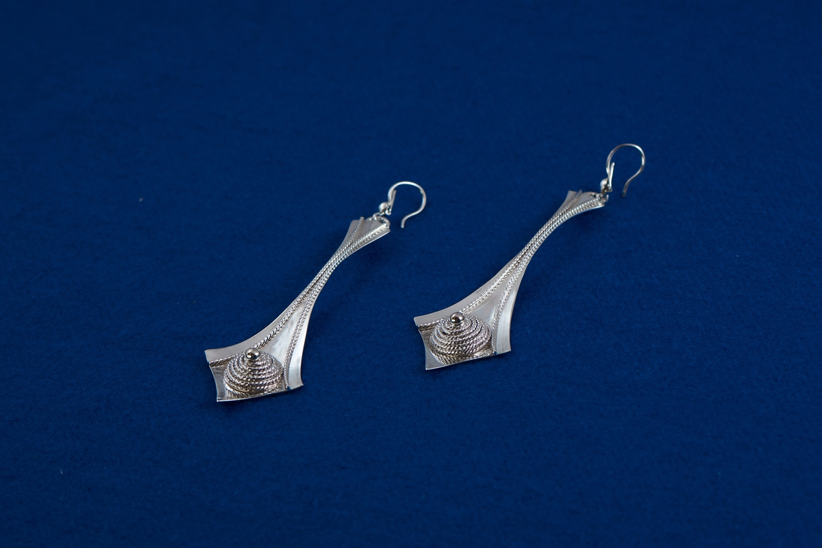 Örhängen i silver tillverkade av Rosa Taikon. De är dekorerade med en för Taikon karaktäristisk form: en spiral av filigrantråd omgärdar en minimal granalie av guld i spiralens mitt. De två örhängena har olika årsstämplar: F10 för 1980 respektive B11 för 2000.