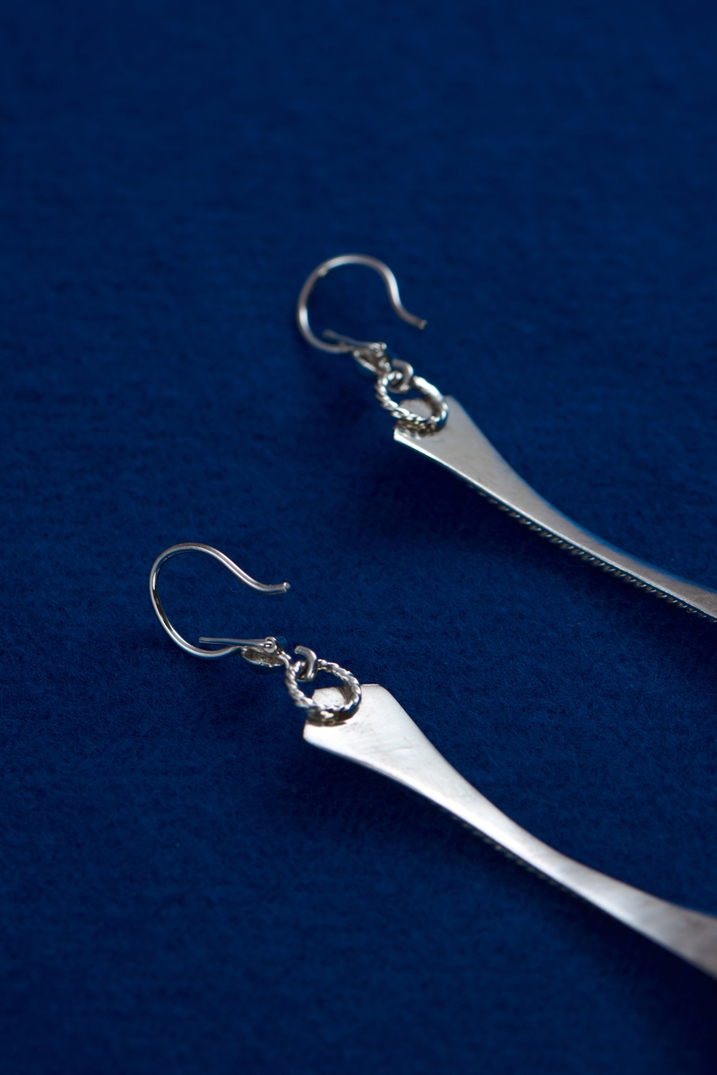 Örhängen i silver tillverkade av Rosa Taikon. De är dekorerade med en för Taikon karaktäristisk form: en spiral av filigrantråd omgärdar en minimal granalie av guld i spiralens mitt. De två örhängena har olika årsstämplar: F10 för 1980 respektive B11 för 2000.