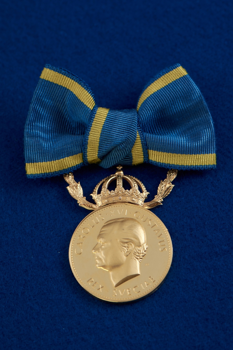 Medalj i guld fäst på blågult band i formen av en rosett. Ovanför den runda medaljen finns en krona mellan två kvistar. År 2010 erhöll Taikon regeringens guldmedalj Illis quorum meruere labores för sitt betydelsefulla konstnärskap “som förenar nyskapande smyckedesign med romska smidestraditioner.” Medaljen överlämnades av dåvarande kulturminister Lena Adelsohn Liljeroth.