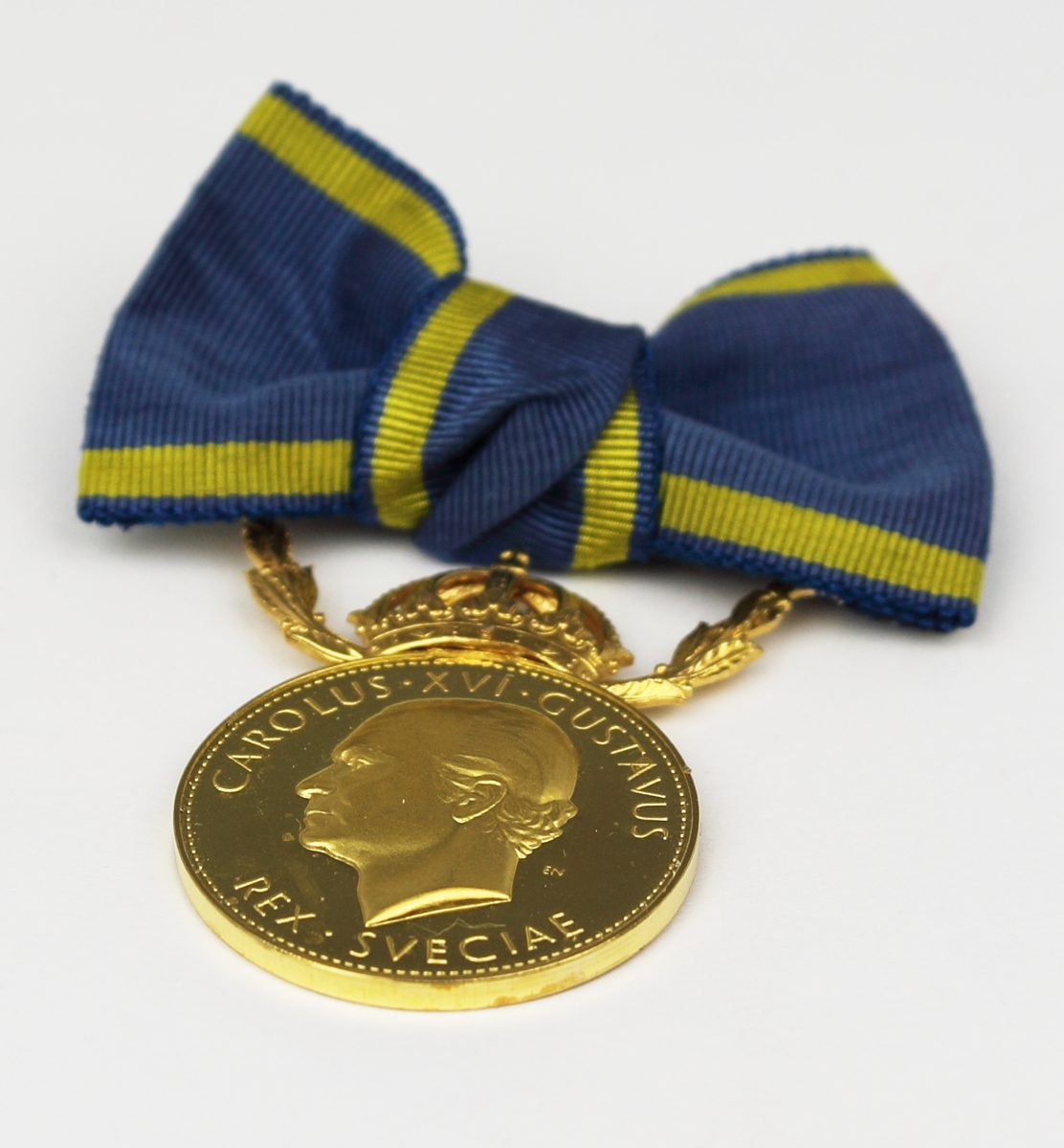 Medalj i guld fäst på blågult band i formen av en rosett. Ovanför den runda medaljen finns en krona mellan två kvistar. År 2010 erhöll Taikon regeringens guldmedalj Illis quorum meruere labores för sitt betydelsefulla konstnärskap “som förenar nyskapande smyckedesign med romska smidestraditioner.” Medaljen överlämnades av dåvarande kulturminister Lena Adelsohn Liljeroth.