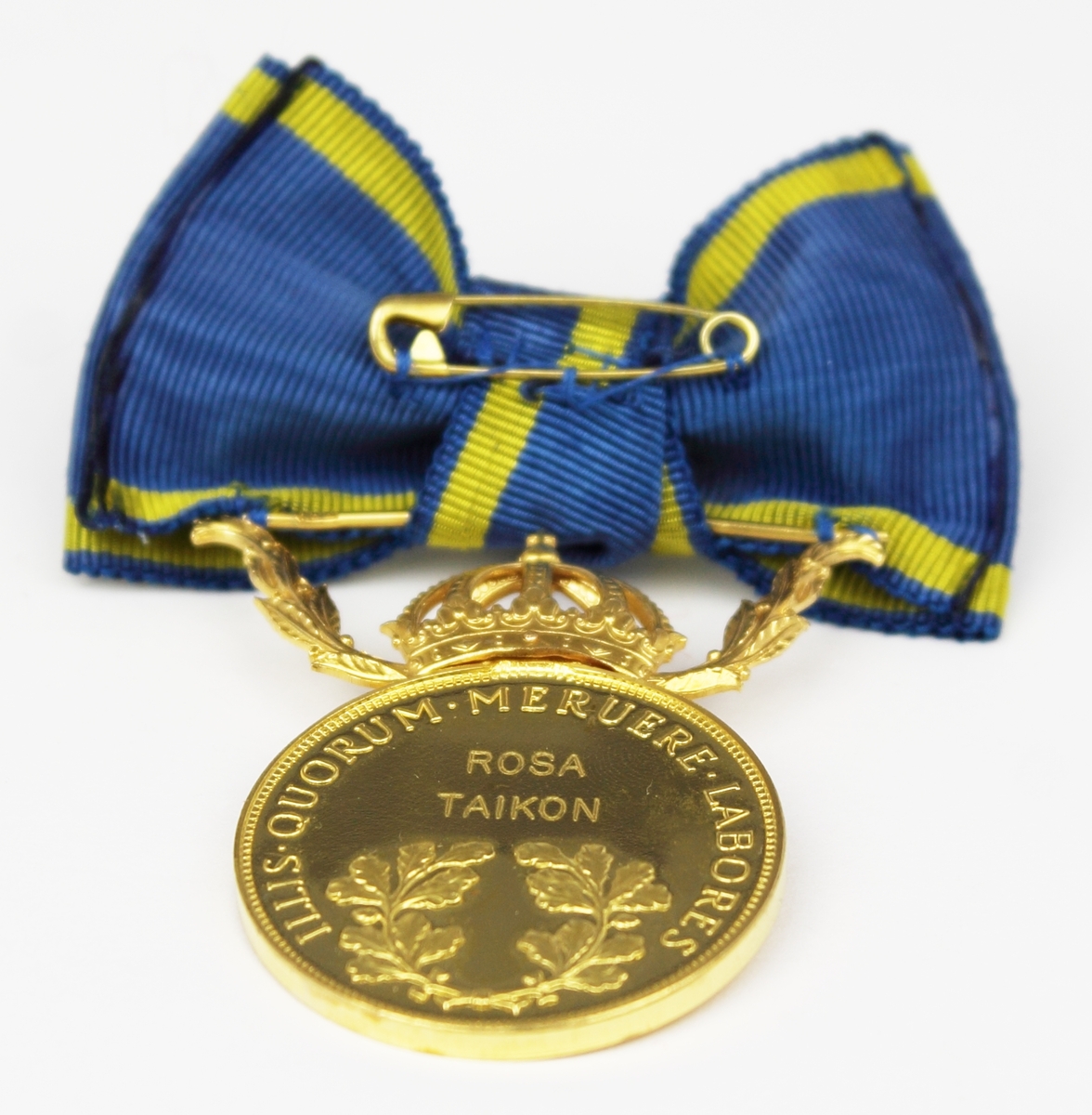 Medalj i guld fäst på blågult band i formen av en rosett. Ovanför den runda medaljen finns en krona mellan två kvistar. År 2010 erhöll Taikon regeringens guldmedalj Illis quorum meruere labores för sitt betydelsefulla konstnärskap “som förenar nyskapande smyckedesign med romska smidestraditioner.” Medaljen överlämnades av dåvarande kulturminister Lena Adelsohn Liljeroth.