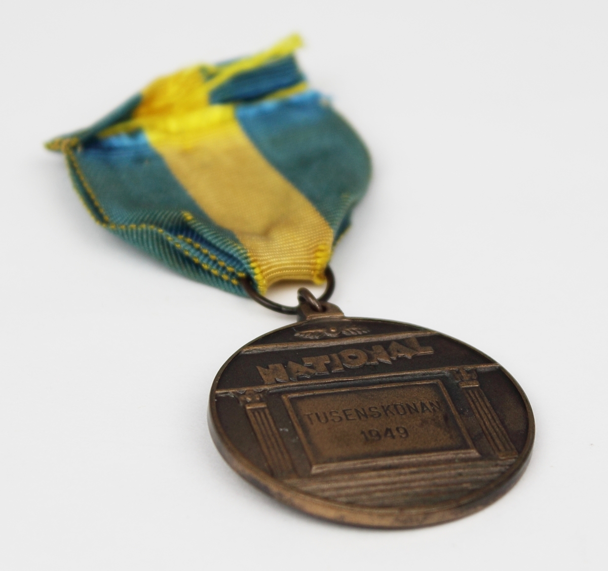 Medalj i brons fäst på blågult band. Medaljen har rund form med en naken kvinna i relief på framsidan. Medaljen var förstapriset i skönhetstävlingen "Tusensköna" på Nalen år 1949 och tilldelades Rosa Taikon. Priset var på 1000 kr.