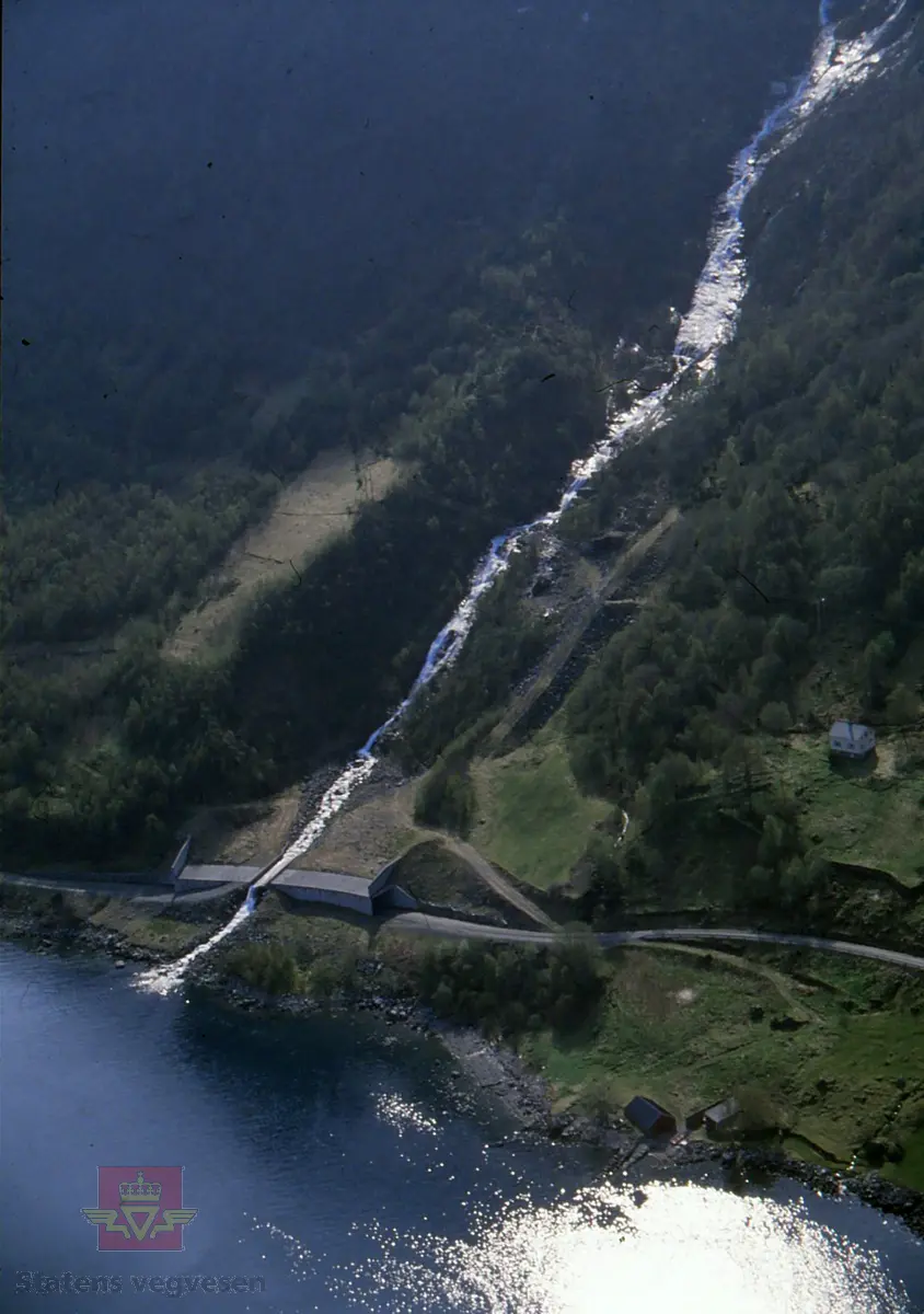 Snøras over fylkesveg 65 Standal - Festøy i Ørsta kommune.

Årsneset, ca 8,1 km fra Festøya. (Kilde: Merking bak på bilde.)

I vegperioden 1986-89 ble det avsatt 9 millioner kroner (1986-kroner) til rassikring på fylkesveg 65, Standal-Festøy. Dette var en stor og samtidig interessant oppgave som Statens vegvesen ikke så seg i stand til å håndtere selv. Derfor ble det innledet et samarbeid med NGI (Norges Geotekniske Institutt).

En var klar over at en ikke kunne regne med nok bevillinger til en "fullgod sikring", dvs. overbygg i betong på alle snørasene på strekningen. I så fall ville dette medføre en samlet lengde på 700 meter og det vil koste ca 40 millioner kroner.

Som en konsekvens la en seg på et "akseptabelt" nivå når det gjaldt regulariteten på vegruten. En mente at en reduksjon på 70-80% totalt på strekningen i "normale" vintre var et mål en kunne håpe på.

Planleggingen skjedde i samarbeid med vegbrukerne og vedlikeholdet med mål om å sikre hele strekningen og redusere stengningene med 70-80% i en normal vinter.

(Kilde: Statens vegvesen i Møre og Romsdal sitt interne magasin "Veg og Virke" nr. 2/1990, artikkelen "Givande om rassikring i Sæbø", skrevet av Arnold Hustad.)