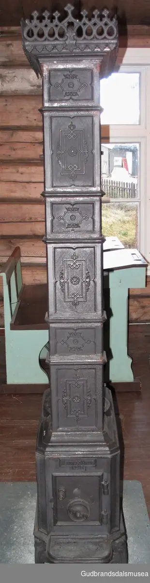 Etasjeovn med tre etasjer. Stiltrekk fra historismen på slutten av 1800-tallet. Brennkammeret har avskårne hjørner, er smalt, rektangulært med ilegging fra kortenden, enkel kokeplate med ringer på toppen samt askebakke foran døren. Står på fire bein av støpejern, bukkeføtter med bruskformer. Etasjekamrene har små dører med smijernsdekor.