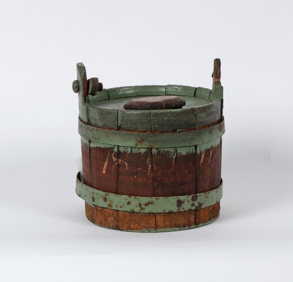 Lagget beholder med lokk og hank. Gjorder av jern. Spuns i helleåpningen i lokket. Hanken er ødelagt.