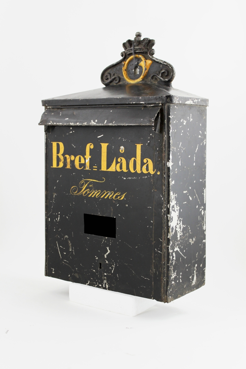 Brevlåda med sluttande tak mot fronten och respektive gavel. Ett postemblem är fäst vid bakstycket på taket. Ett brevinlägg med klaff är placerat i den övre delen av fronten. Under brevlinlägget står texten:"Bref-Låda och därunder "Tömmes". Under texten finns en rektangulär lucka där tömningsturerna skall anges.

Brevlådan töms från botten.