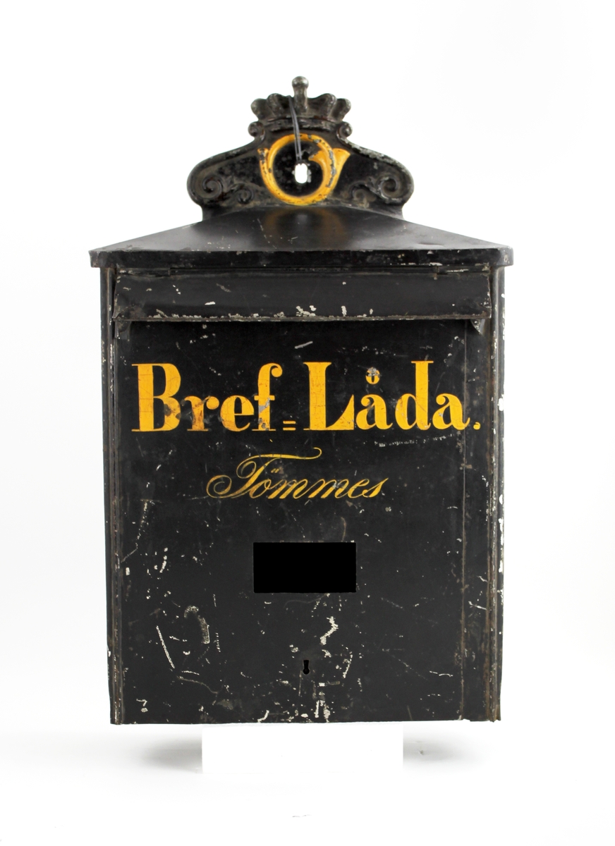 Brevlåda med sluttande tak mot fronten och respektive gavel. Ett postemblem är fäst vid bakstycket på taket. Ett brevinlägg med klaff är placerat i den övre delen av fronten. Under brevlinlägget står texten:"Bref-Låda och därunder "Tömmes". Under texten finns en rektangulär lucka där tömningsturerna skall anges.

Brevlådan töms från botten.