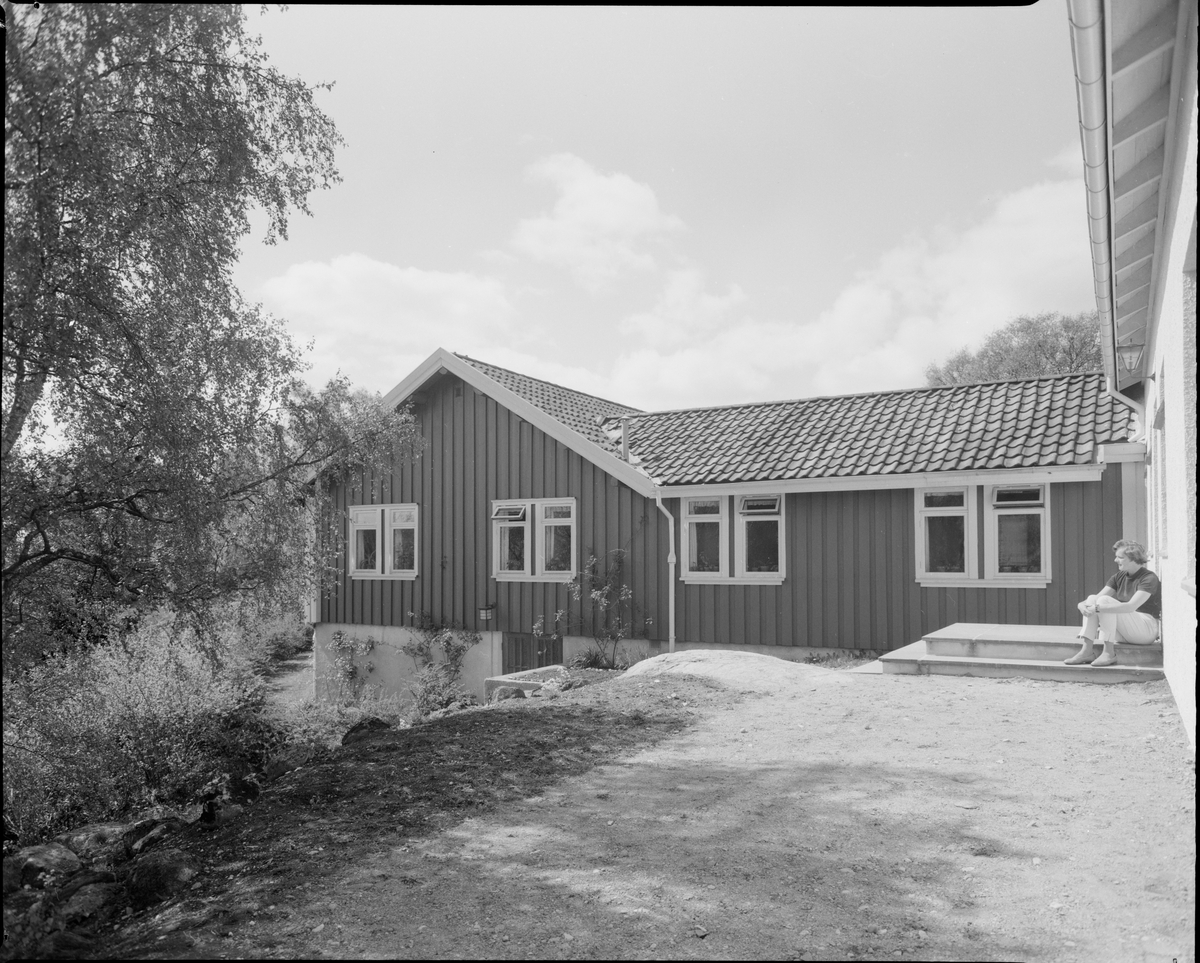 Bærumsgården på Bakkebø hjem og arbeidsskole. En kvinne sitter på trappeoppgangen.